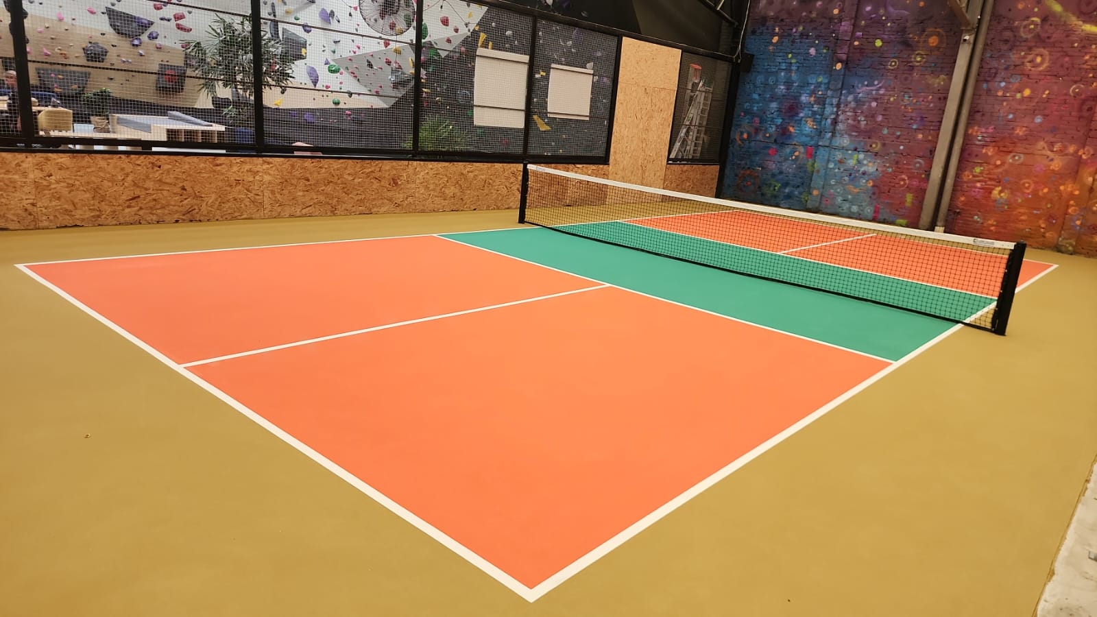 Cancha de pickleball indoor construida en gimnasio con colores naranja y verde sistema Laykold