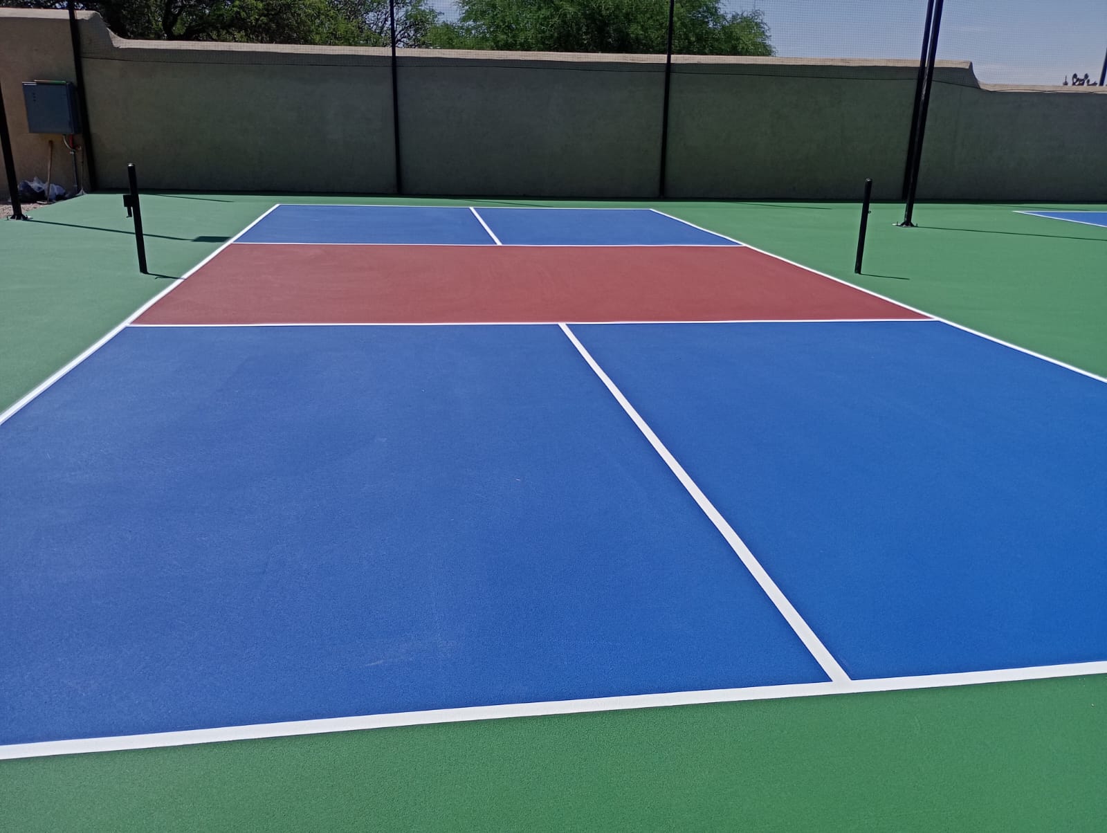 Cancha de pickleball profesional construida por CanchasdePickleball.mx en club deportivo con colores azul y terracota según estándar USAPA