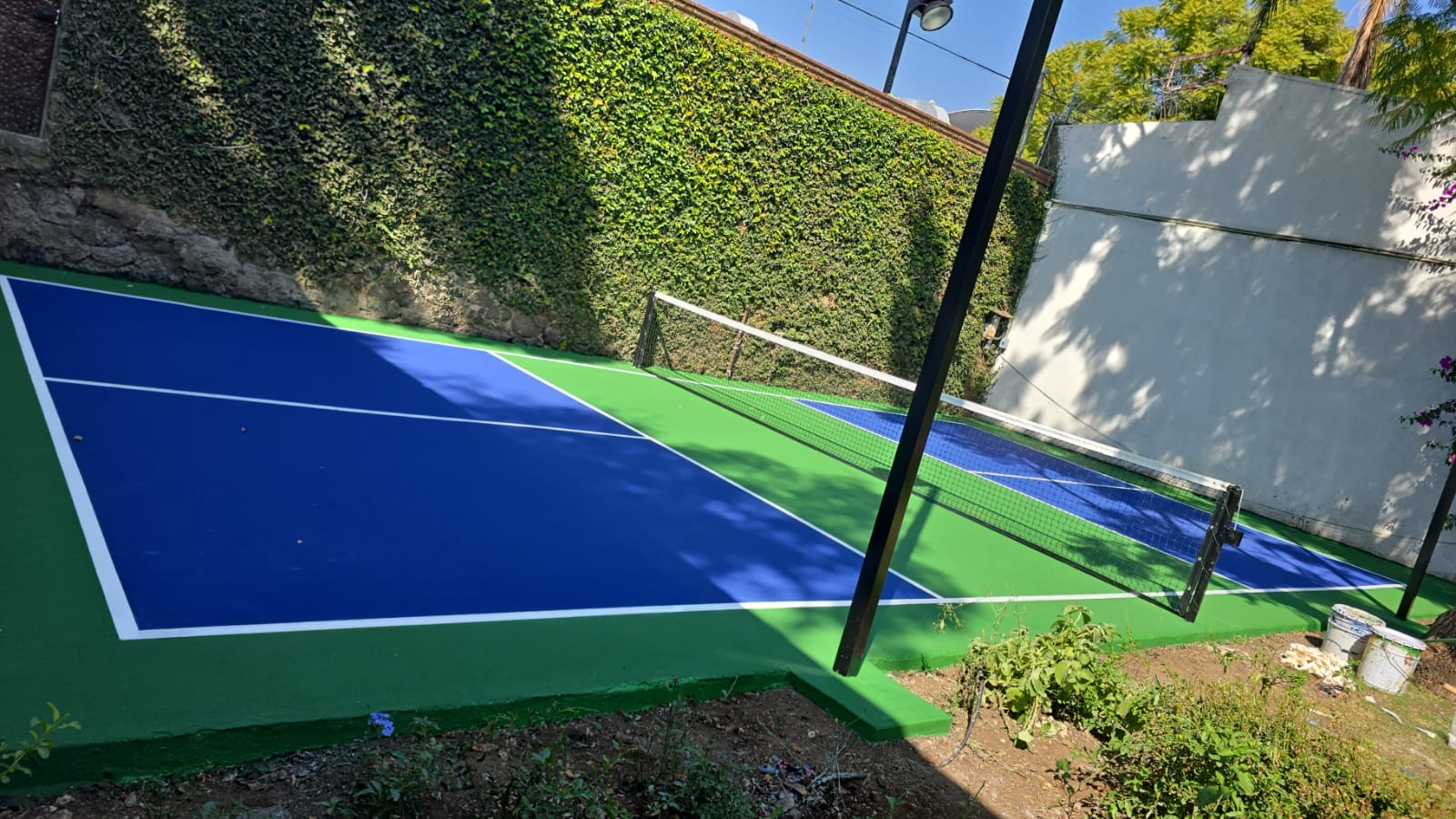 Renovación de cancha de pickleball con pintura acrílica verde y azul tipo Laykold en jardín residencial México